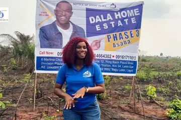 Dala Real Estate agent at the Asaba Phase 3 estate signboard